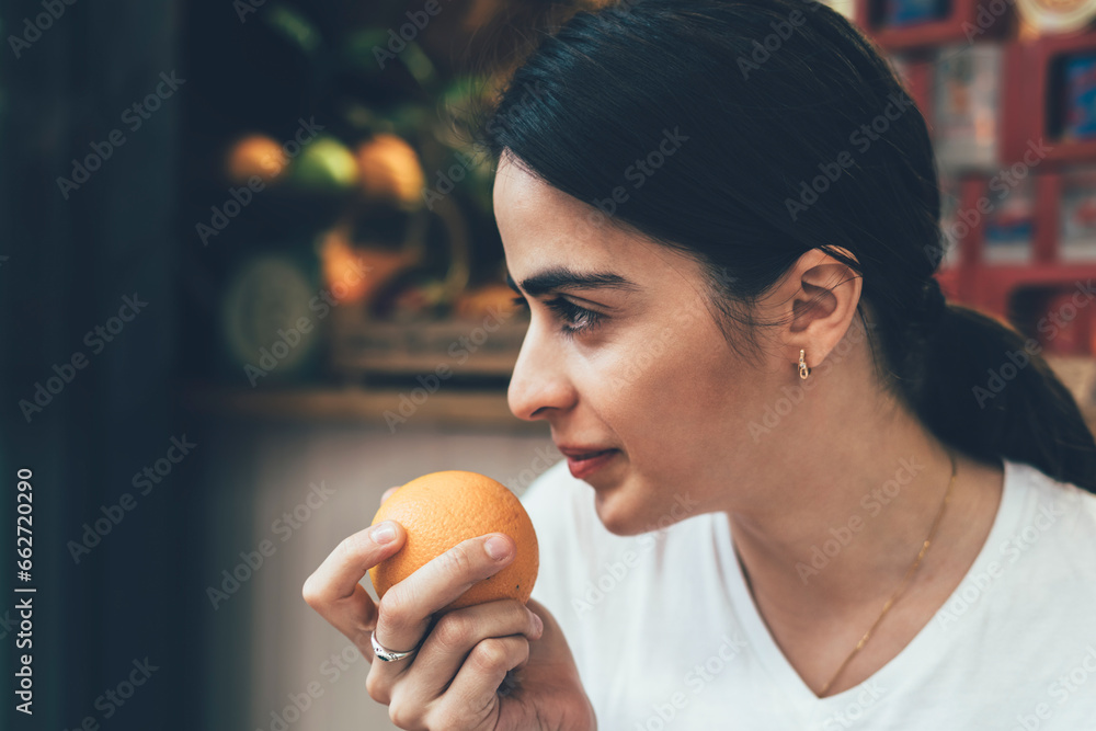 Young woman smelling orange in market