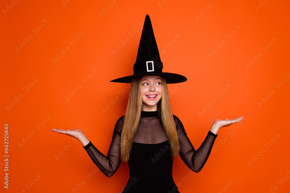 Photo of beautiful teenager schoolgirl sorcerer look hands hold empty space scales proposition isolated on orange color background