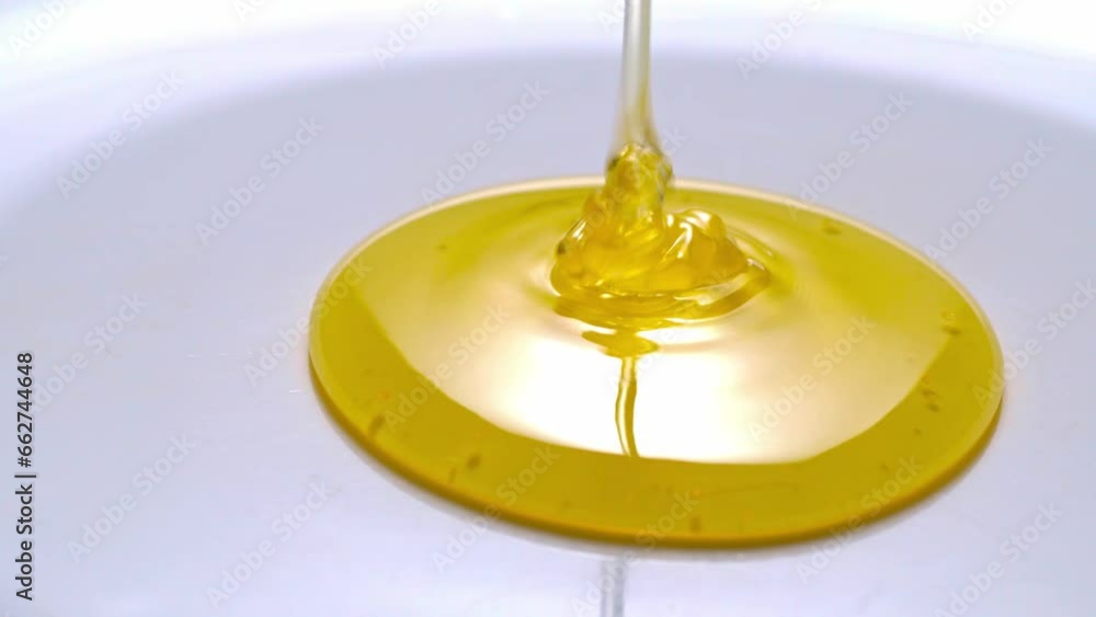 Honey pouring and spreading on a white plate close-up Honey pouring and spreading on a white plate close-up