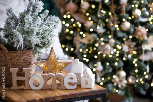 Beautiful holiday card. The concept of a happy new year and Christmas 2024. Christmas trees, Scandinavian white houses and a home sign on a wooden table in a cozy living room. photo