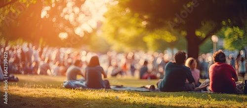 Family members enjoy an outdoor picnic and open air public concert in a park sitting on grass With copyspace for text