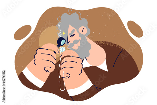 Elderly man jeweler examines silver necklace through magnifying glass to evaluate accessory