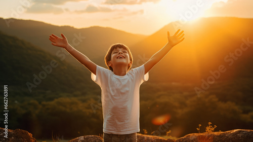 Boy kid wearing a white t-shirt joyfully raises his arms, his vibrant energy shining against a captivating nature landscape at sunset , portraying an aura of positivity and exuberance photo