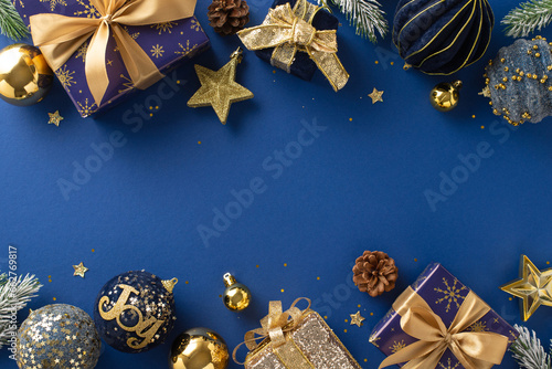 Glitzy Seasonal Elegance. Top view of shimmering blue and gold-wrapped gifts, festive baubles, brilliant star, glitter, pine cones, frost-covered fir twigs on sumptuous blue background for advert