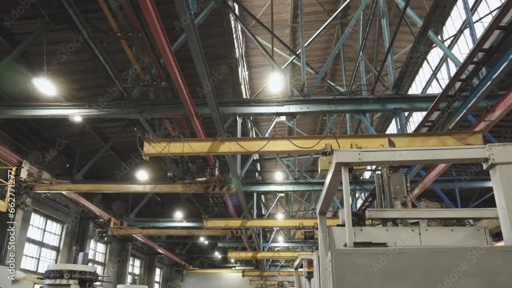 Ceiling of factory production building with installed metal structures, beams and hoists and roof lanterns. Organization of lighting in an old shutdown production facility. Ceiling of factory production building with installed metal structures, beams and hoists and roof lanterns. Organization of lighting in an old shutdown production facility.