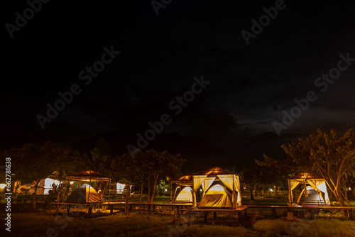 Canvas Print camping tent with tarp or flysheet on grass courtyard and warm night light under