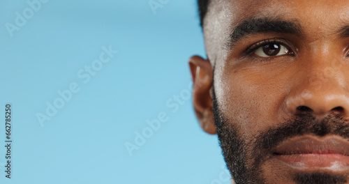 Half, face and serious black man in studio, blue background and mockup space with confidence or advertising. Portrait, closeup and marketing for skincare, wellness or healthy dermatology care