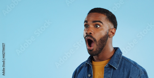 Vászonkép Black man, surprise announcement and shock on face, expression and drama on blue background