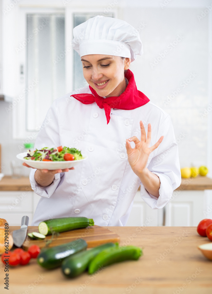 Female chef with plate of vegetable salad Female chef with plate of vegetable salad
