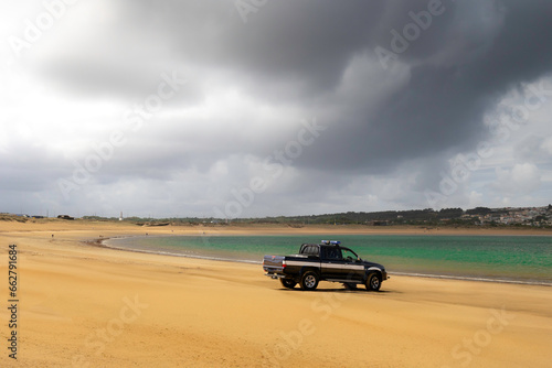 Truck on the sand with stormy skies, in the beach of Sao Martinho do Porto - Portugal