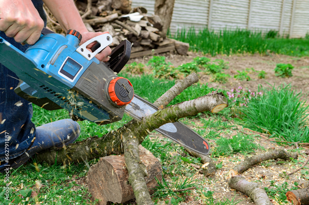 Work with the power tool. Electric in the hands of a man. Firewood Work with the power tool. Electric in the hands of a man. Firewood