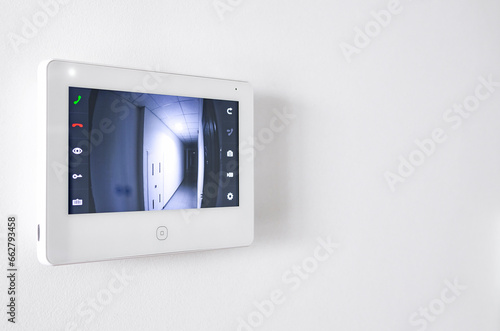 A white video intercom screen on a white apartment wall