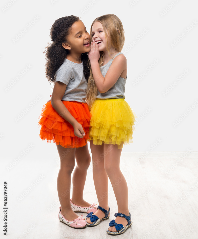 two little pretty girls in colorful skirts talking and laughing isolated on white background two little pretty girls in colorful skirts talking and laughing isolated on white background