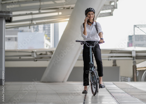 Fototapeta Naklejka Na Ścianę i Meble -  Eco friendly, businesswoman ride bicycle in urban to reduce carbon footprint. Beautiful woman environment preservation person commuting with bicycling. Cycling, alternative transport for clean energy.