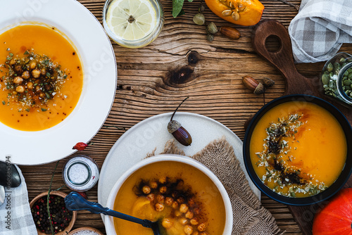 Bowls with vegan pumpkin soup on wooden table, directly above