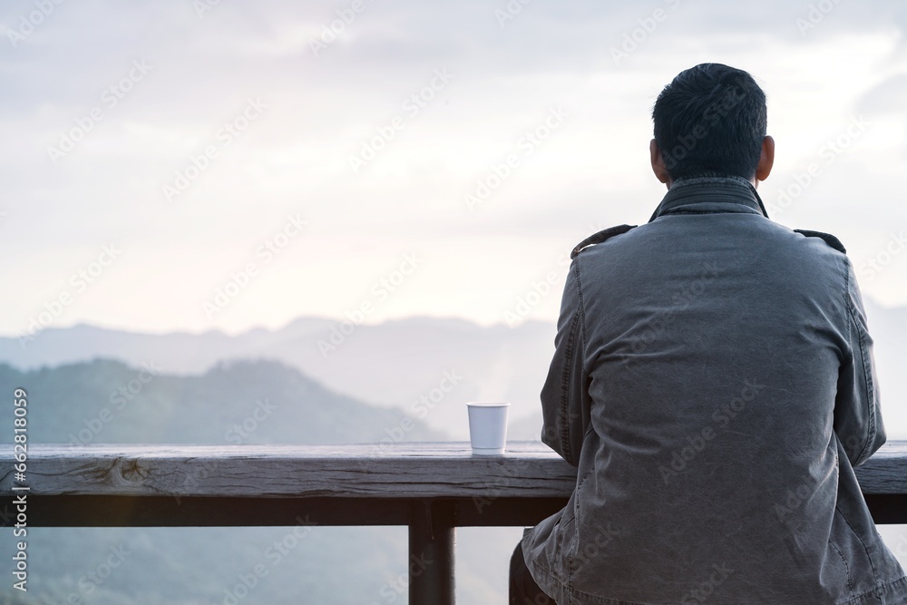 Traveler or tourist in coat drinks hot coffee and looks at mountain view in the morning