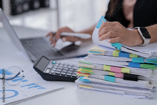 Business Documents concept: Employee woman hands working in Stacks paper files for searching and checking unfinished.