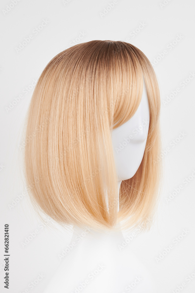Natural looking blonde fair wig on white mannequin head. Short hair cut on the plastic wig holder isolated on white background, side view. Natural looking blonde fair wig on white mannequin head. Short hair cut on the plastic wig holder isolated on white background, side view.