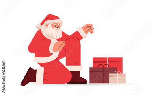 santa claus in red costume sitting on floor near gift boxes happy new year merry christmas holidays celebration concept