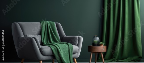 Green blanket on gray sofa in bright living room with empty poster and armchair With copyspace for text