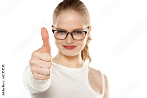Smiling woman with glasses showing thumb up on a white background