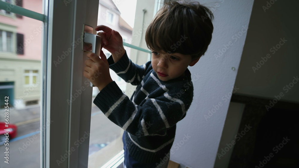 Child holding into window knob. Danger concept of small boy near glass from second floor apartment residence Child holding into window knob. Danger concept of small boy near glass from second floor apartment residence
