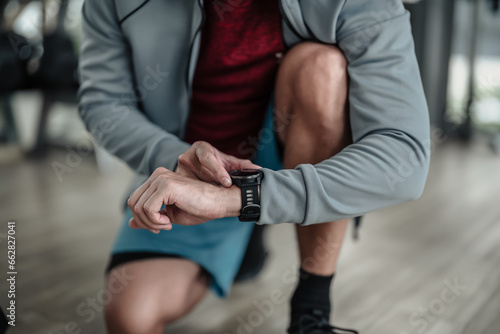A man checking at smartwatch during training at gym. Fitness, workout and traning at concept.