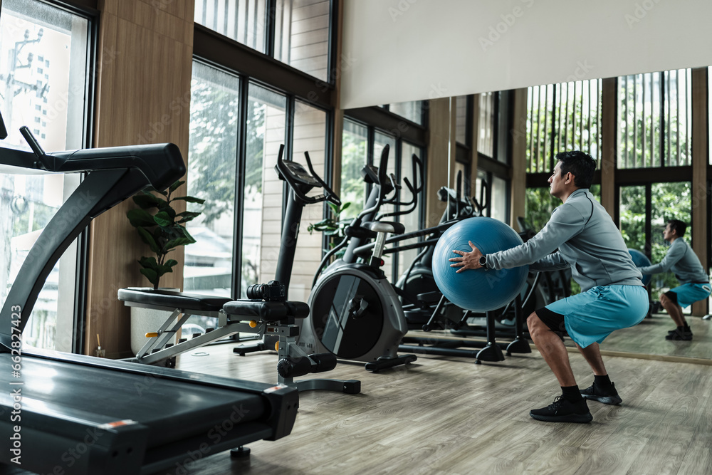 Fototapeta premium A man use pilates ball to squat. Fitness, gym, workout and lifestyle concept.