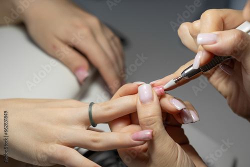 Female hands and tools for manicure  process of performing manicure in beauty salon. Nail care procedure in a beauty salon. Gloved hands of a skilled manicurist cutting cuticles. Concept spa body care