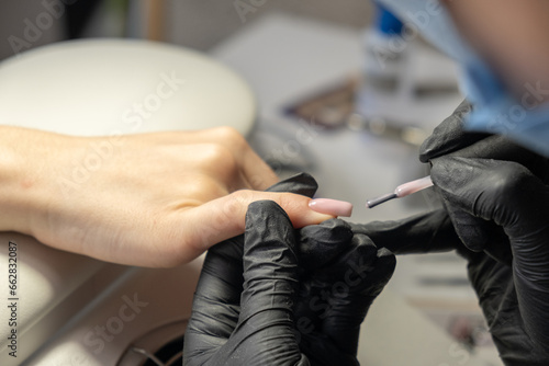 Female hands and tools for manicure  process of performing manicure in beauty salon. Nail care procedure in a beauty salon. Gloved hands of an experienced manicurist in gloves are varnished nails