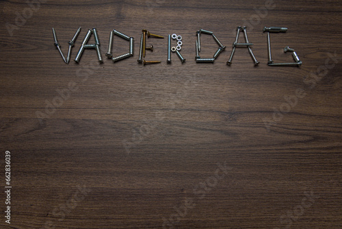 Dutch text Vaderdag made of screws on a dark wooden background, Father's Day concept photo