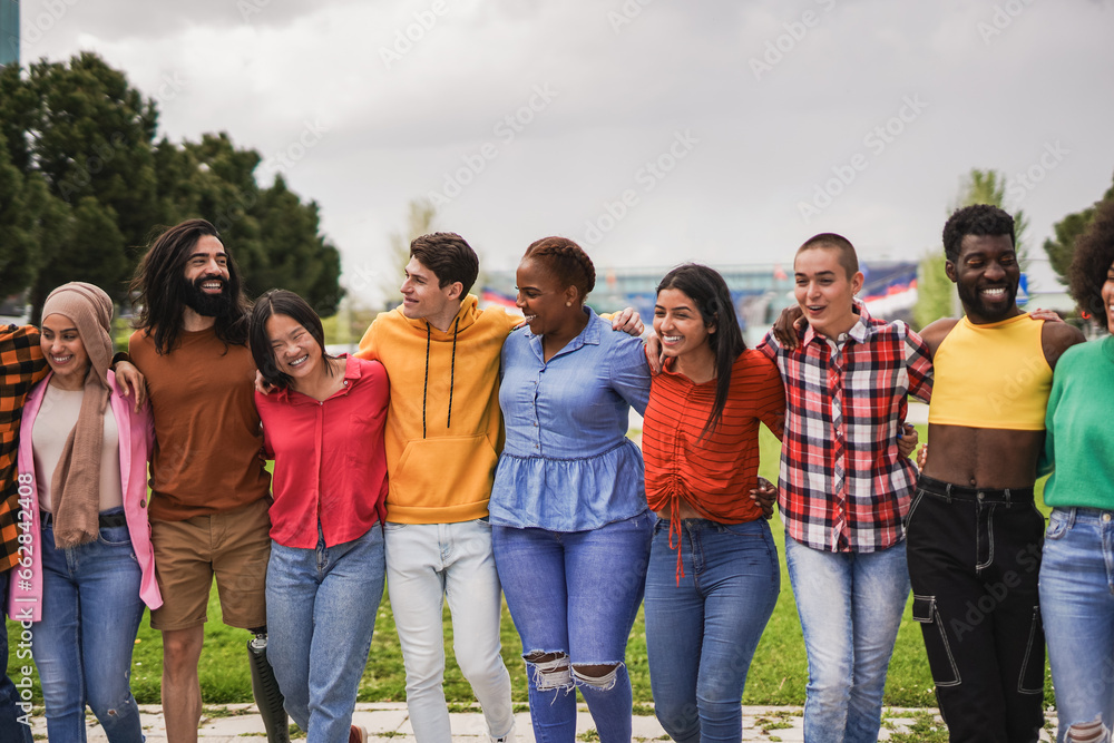 Happy multiracial young people walking and hugging each other in the city - Diversity and friendship concept Happy multiracial young people walking and hugging each other in the city - Diversity and friendship concept