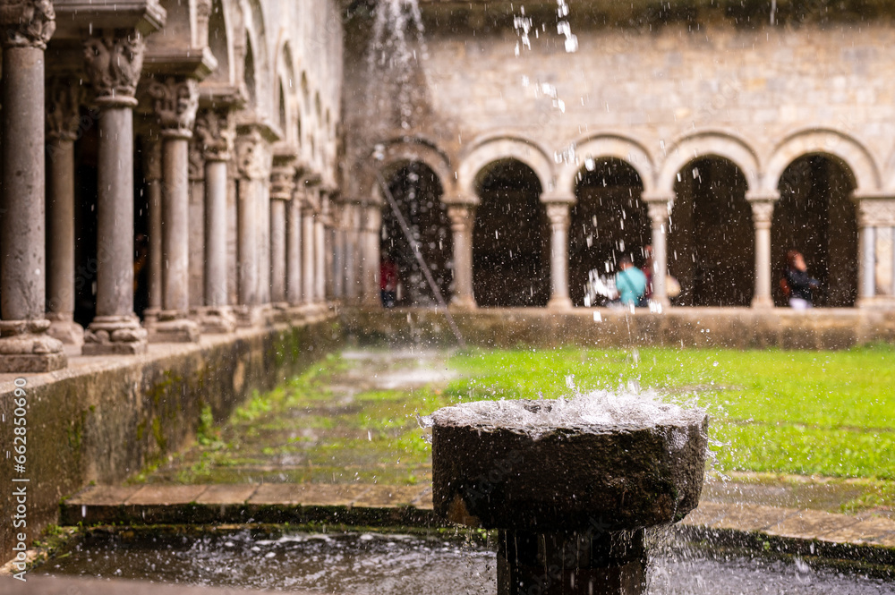 Detail of the cloister of the Cathedral of Girona, Spain. Water is falling from the cloister's roof into a small water basin in the garden.