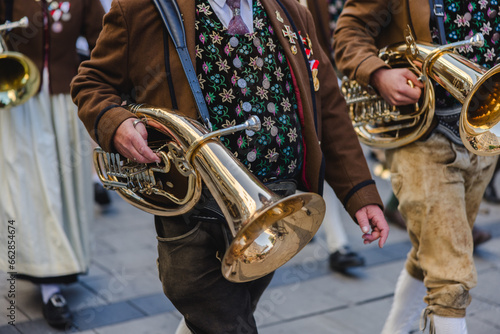 A man in traditional Bavarian attire carrying a wind instrument as part of a traditional brass band photo
