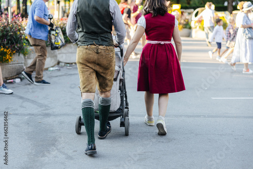 Man wearing Lederhosen and woman wearing the traditional Bavarian Dirndl at the Oktoberfest in Munich, Germany walking side by side close-up