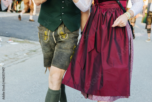Man wearing Lederhosen and woman wearing the traditional Bavarian Dirndl at the Oktoberfest in Munich, Germany walking side by side close-up