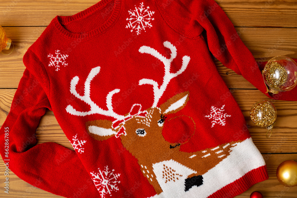  Warm Christmas sweaters. Winter holiday knitted sweaters with pattern on a wooden background with Christmas decorations.Stack of warm Christmas sweaters.Top view
