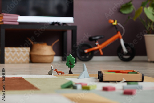 Close up background image of wooden toy set with bricks and animals on plush carpet in cozy childrens room, copy space