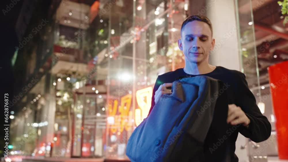 The man sitting on a bench and opens his backpack with laptop in a case The man sitting on a bench and opens his backpack with laptop in a case