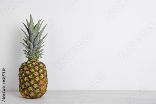 Whole ripe pineapple on white wooden table. Space for text