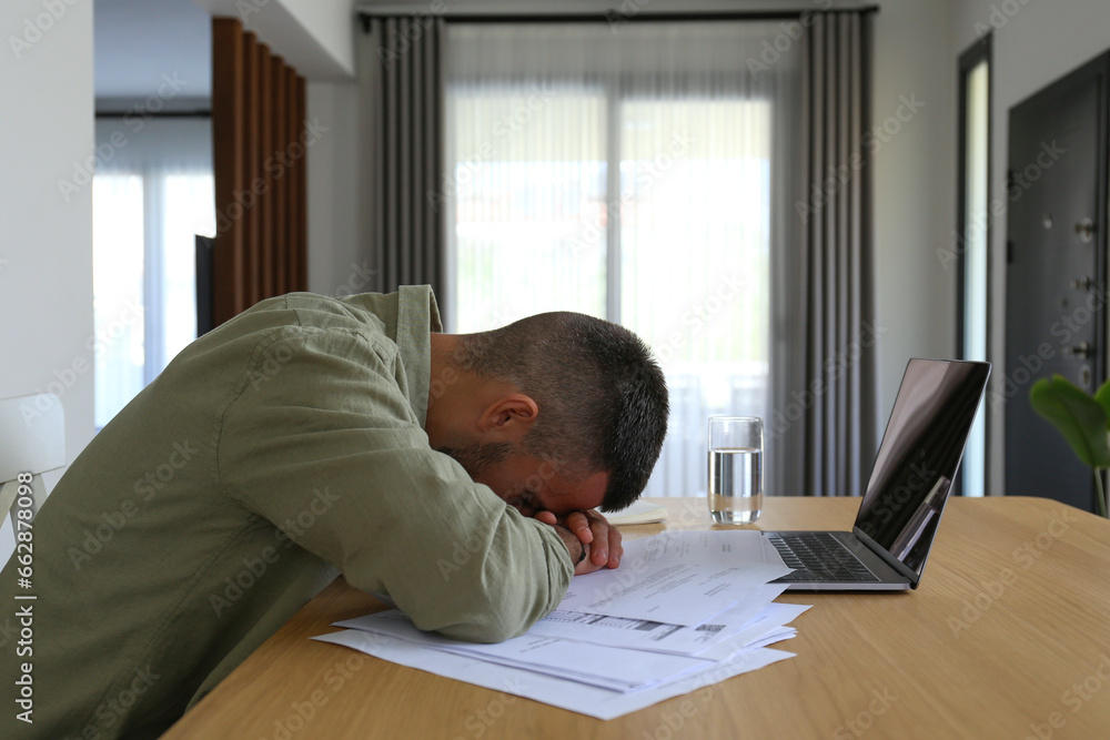 Exhausted young man tired of going through his bills and taxes. Close up, copy space, interior background. Exhausted young man tired of going through his bills and taxes. Close up, copy space, interior background.