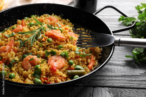 Tasty rice with shrimps and vegetables in frying pan on grey wooden table, closeup