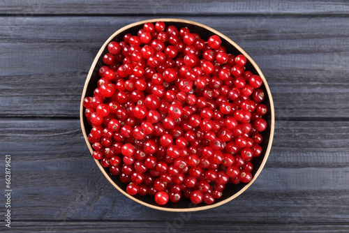 Ripe red currants in bowl on wooden rustic table, top view