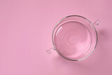 Empty glass pot on pink background, top view. Space for text