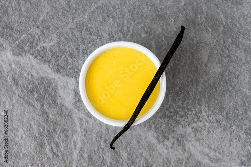 Homemade vanilla custard in white bow on gray stone background. Top view