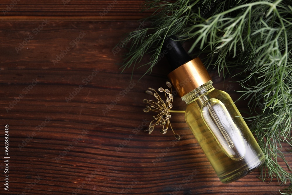 Fototapeta premium Bottle of essential oil and fresh dill on wooden table, flat lay. Space for text