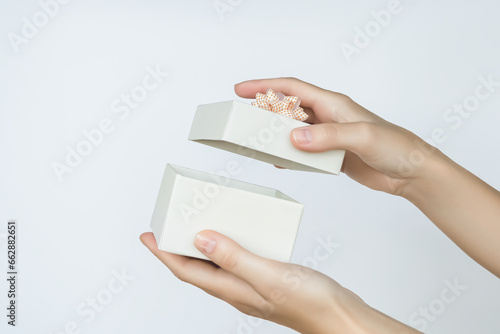 Fotografie female hands open a cardboard gift box on a white background