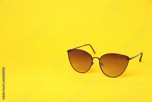 New stylish sunglasses on yellow background, space for text