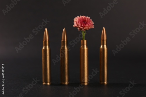 Bullets and cartridge case with beautiful flower on black background