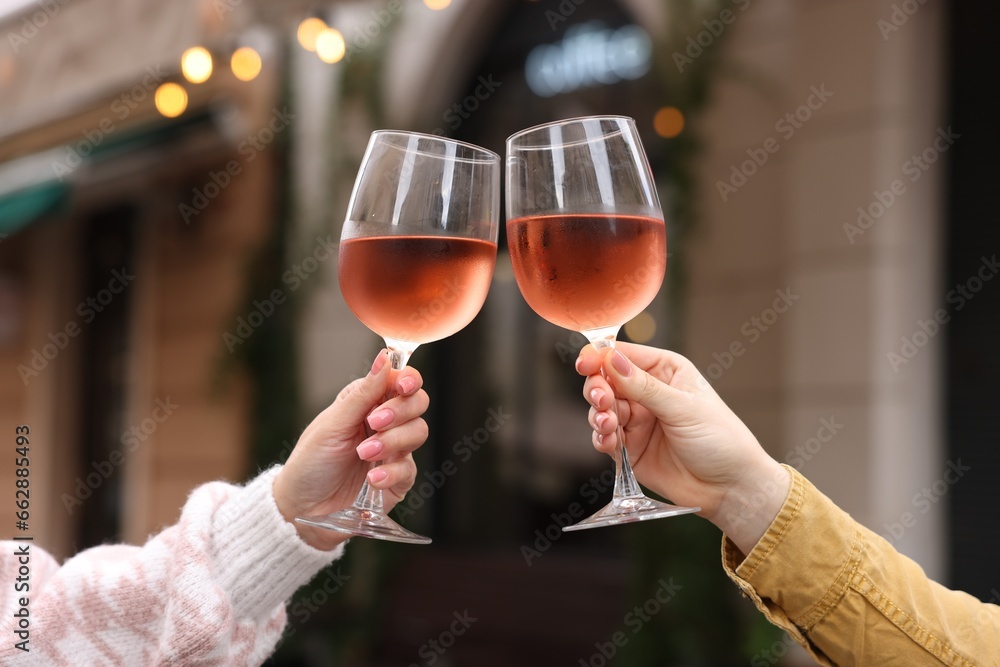 Women clinking glasses with rose wine outdoors, closeup Women clinking glasses with rose wine outdoors, closeup